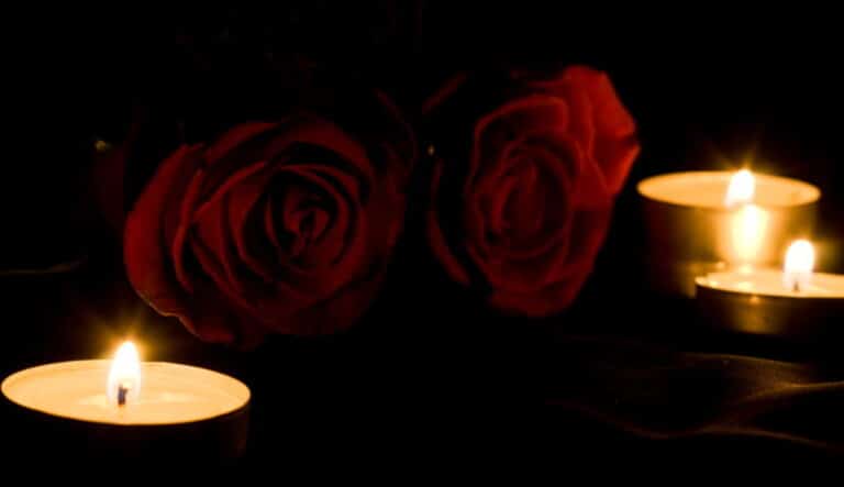 Two roses next to lit candles in memorial for a wrongful death.